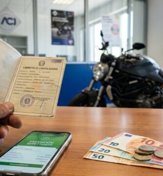 Immagine dell'interno di un'officina con vista su una scrivania con documenti e denaro, sullo sfondo una motocicletta.