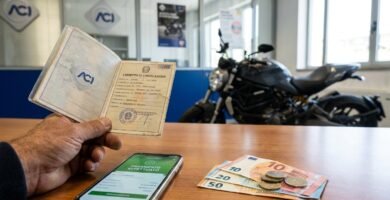 Immagine dell'interno di un'officina con vista su una scrivania con documenti e denaro, sullo sfondo una motocicletta.
