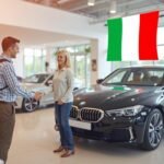 Immagine di due persone in una concessionaria di automobili che concludono un affare accanto a un'auto
